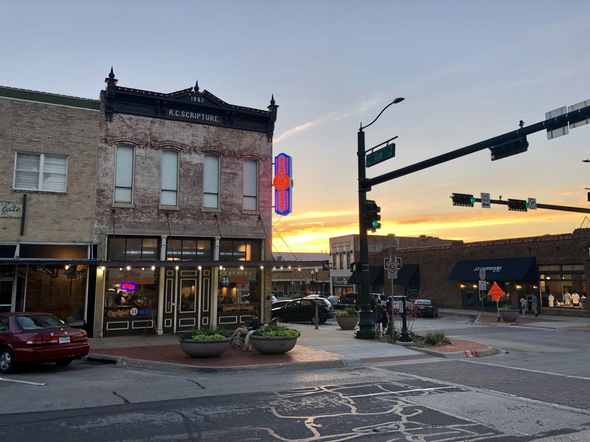 A small-town Main Street at dusk, lights coming on
